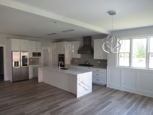 kitchen with sink, appliances with stainless steel finishes, white cabinetry, a center island with sink, and custom exhaust hood