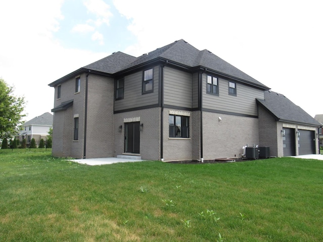 back of house with central AC unit and a yard