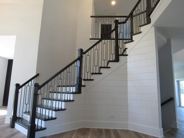 stairs featuring hardwood / wood-style flooring and a high ceiling