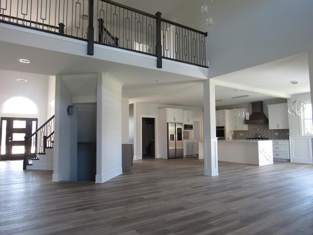 unfurnished living room featuring a high ceiling and dark hardwood / wood-style floors