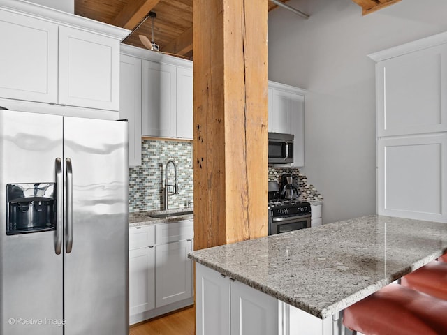 kitchen featuring a breakfast bar, sink, white cabinetry, stainless steel appliances, and backsplash