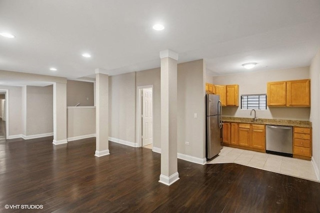 kitchen featuring stainless steel appliances, light stone countertops, hardwood / wood-style flooring, and sink