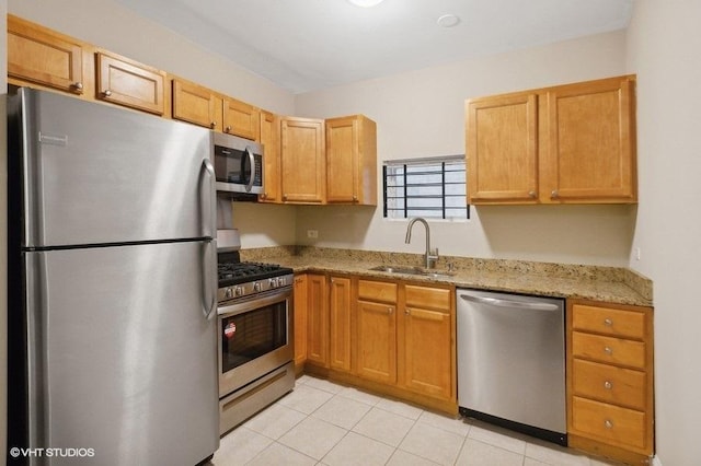 kitchen featuring light tile patterned flooring, stainless steel appliances, light stone countertops, and sink