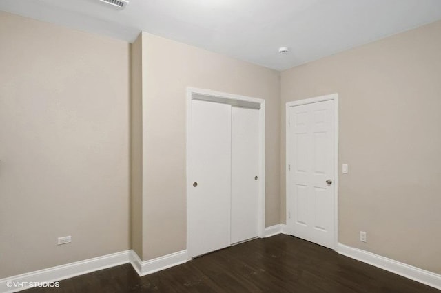 unfurnished bedroom with dark wood-type flooring and a closet