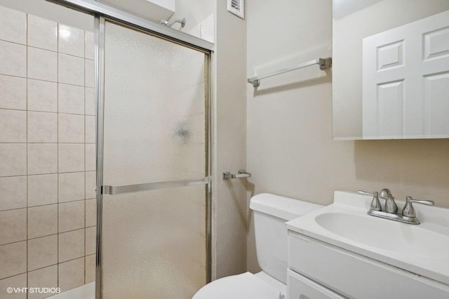 bathroom featuring vanity, toilet, and a shower with door