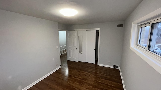 unfurnished bedroom featuring dark hardwood / wood-style floors and a closet