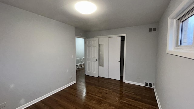 unfurnished bedroom featuring dark wood-type flooring and a closet