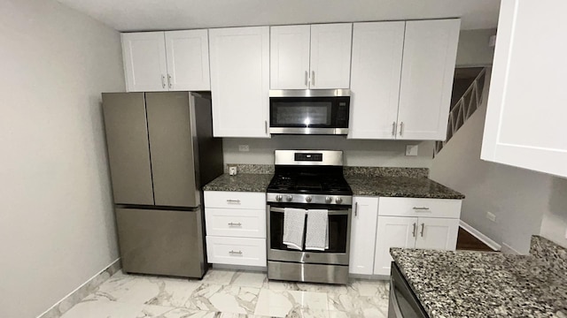 kitchen featuring dark stone countertops, stainless steel appliances, and white cabinets