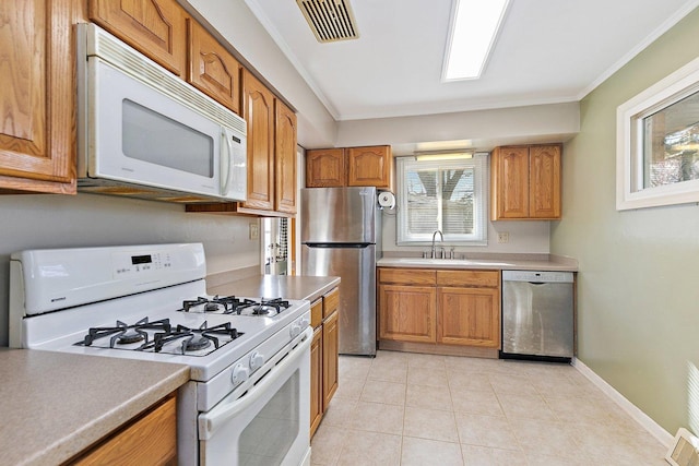 kitchen with crown molding, appliances with stainless steel finishes, sink, and light tile patterned floors