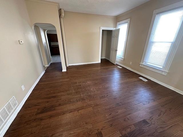 spare room featuring crown molding and dark hardwood / wood-style flooring