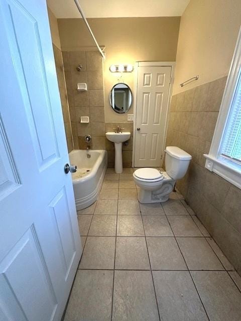 full bathroom featuring tile patterned floors, toilet, sink, tile walls, and tiled shower / bath combo