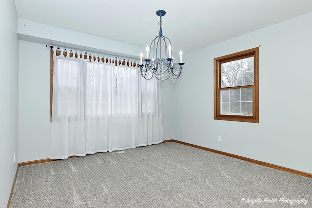 carpeted empty room featuring a chandelier