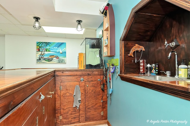 bar featuring a paneled ceiling and sink