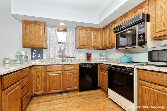 kitchen with sink, light stone counters, light hardwood / wood-style floors, and black appliances