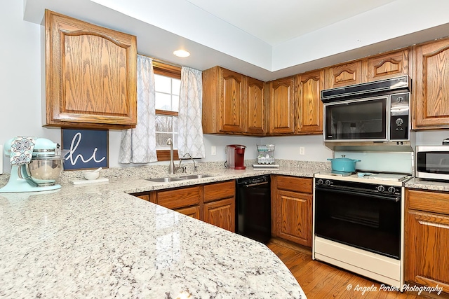 kitchen with light stone countertops, sink, light hardwood / wood-style flooring, and black appliances