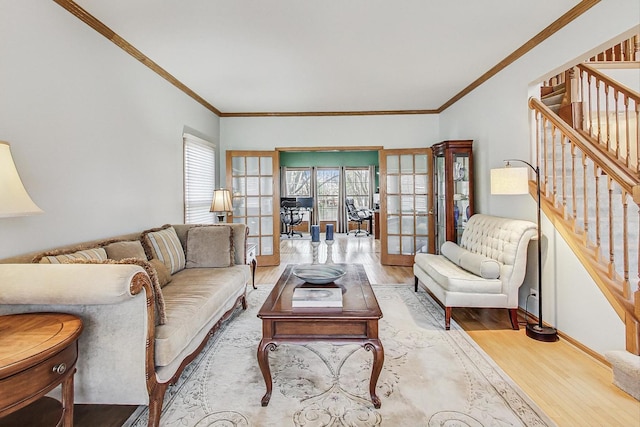 living room with french doors, crown molding, and light wood-type flooring