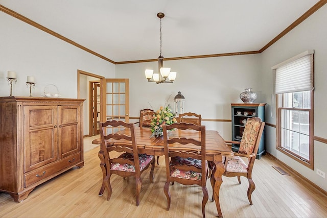 dining space with crown molding, a notable chandelier, and light hardwood / wood-style floors