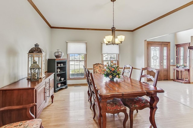 dining area featuring crown molding, an inviting chandelier, and light hardwood / wood-style floors