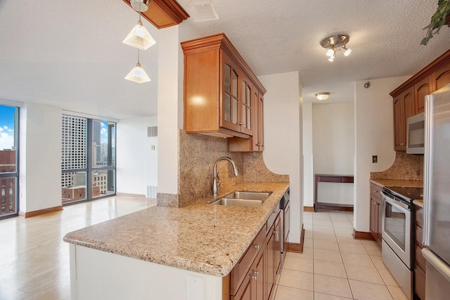 kitchen with pendant lighting, sink, stainless steel appliances, light stone countertops, and decorative backsplash