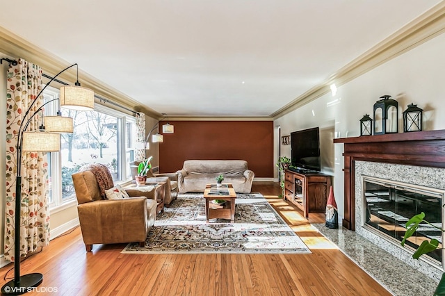 living area with light wood-type flooring, baseboards, a fireplace, and ornamental molding