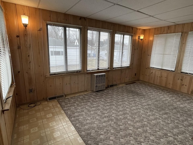 unfurnished sunroom with heating unit and a drop ceiling