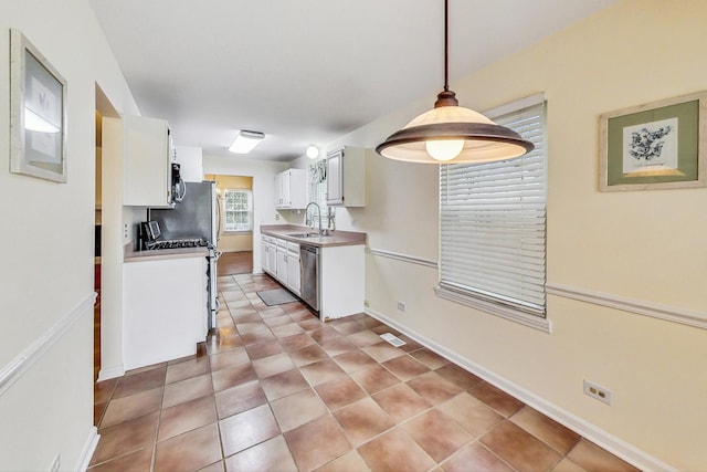 kitchen featuring decorative light fixtures, white cabinetry, sink, light tile patterned floors, and stainless steel appliances