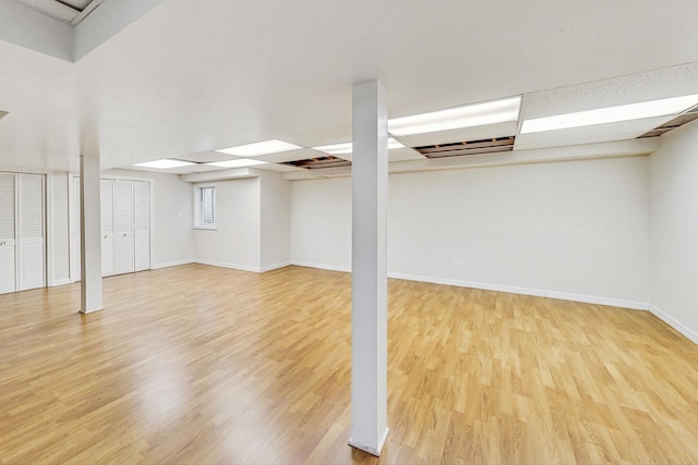 basement featuring a drop ceiling and light hardwood / wood-style flooring