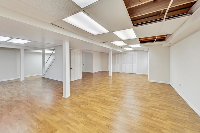 basement featuring a paneled ceiling and light wood-type flooring