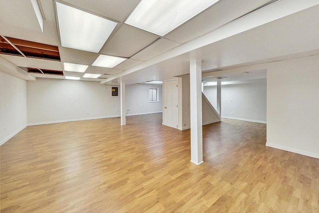 basement featuring a paneled ceiling and light hardwood / wood-style floors