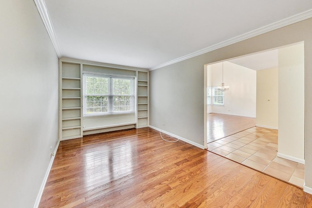 spare room featuring an inviting chandelier, ornamental molding, and light hardwood / wood-style floors