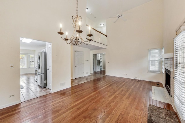 unfurnished living room with a towering ceiling, an inviting chandelier, and light hardwood / wood-style flooring