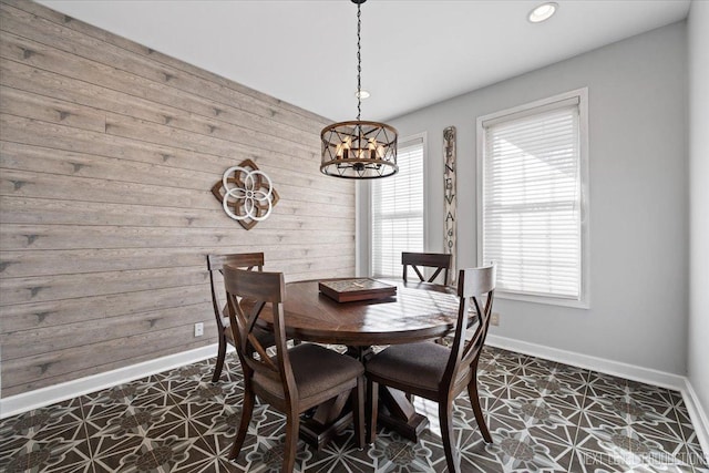 tiled dining area featuring a notable chandelier and wooden walls