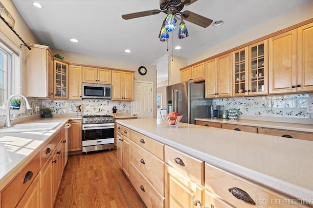 kitchen featuring sink, ceiling fan, appliances with stainless steel finishes, light hardwood / wood-style floors, and decorative backsplash