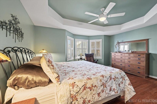 bedroom with ceiling fan, dark hardwood / wood-style flooring, and a raised ceiling