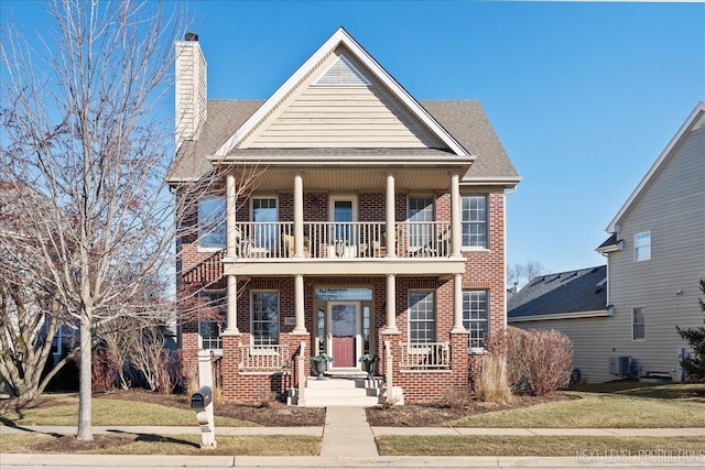 view of front facade with a front yard, a balcony, cooling unit, and covered porch