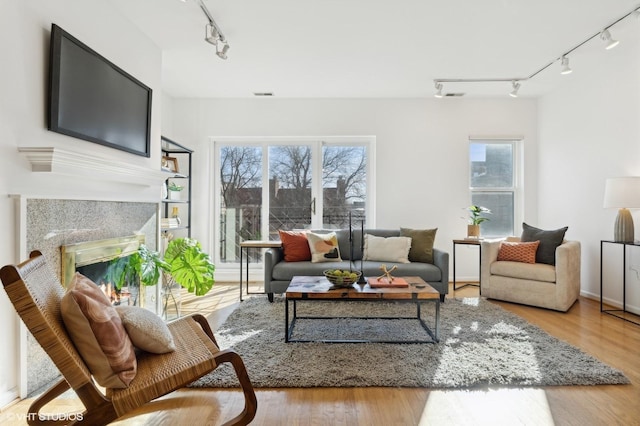 living room featuring a high end fireplace, rail lighting, and light wood-type flooring