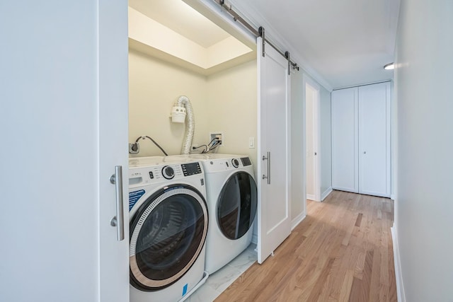 laundry area with a barn door, separate washer and dryer, and light hardwood / wood-style floors