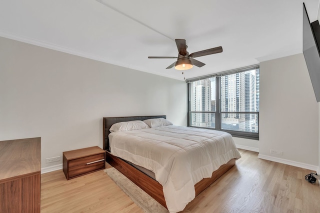 bedroom featuring light hardwood / wood-style flooring, ornamental molding, and ceiling fan