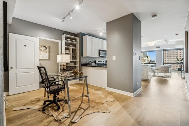 office area with track lighting and light wood-type flooring