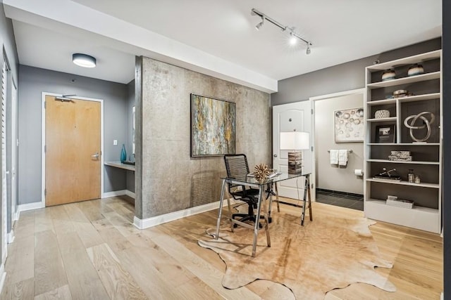 home office with hardwood / wood-style floors and track lighting