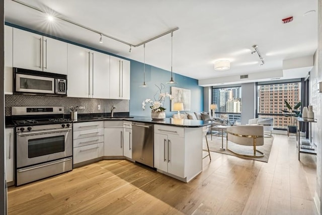 kitchen featuring appliances with stainless steel finishes, pendant lighting, tasteful backsplash, white cabinetry, and kitchen peninsula