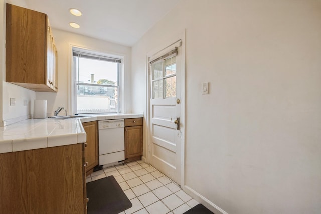 kitchen with tile counters, white dishwasher, and light tile patterned flooring