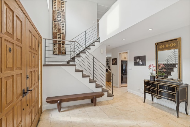 foyer entrance featuring light tile patterned flooring and a towering ceiling