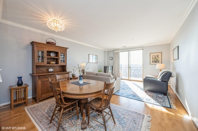 dining space with crown molding, a chandelier, and light hardwood / wood-style flooring