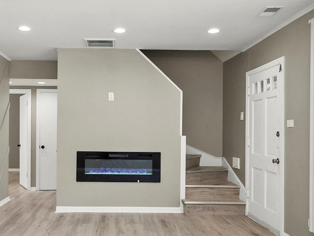 interior space featuring crown molding and light hardwood / wood-style flooring