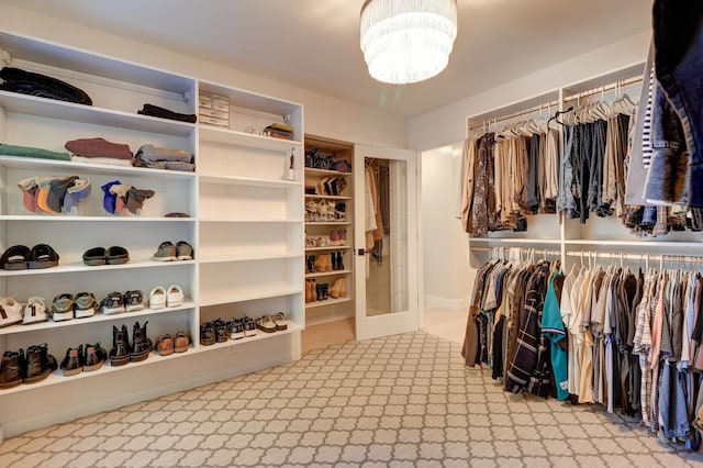 spacious closet with light colored carpet and a chandelier