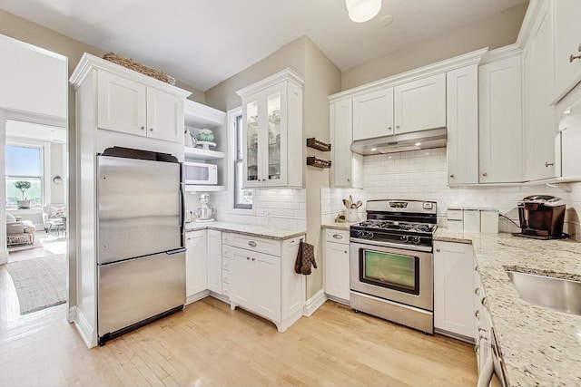 kitchen with light stone counters, light hardwood / wood-style floors, white cabinets, and appliances with stainless steel finishes