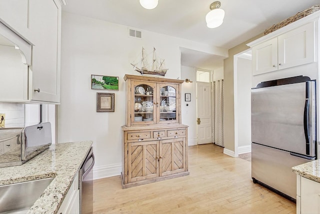 kitchen featuring stainless steel appliances, light stone countertops, and white cabinets