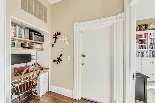 home office with dark hardwood / wood-style floors and built in desk