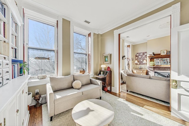 sitting room with ornamental molding and light hardwood / wood-style flooring